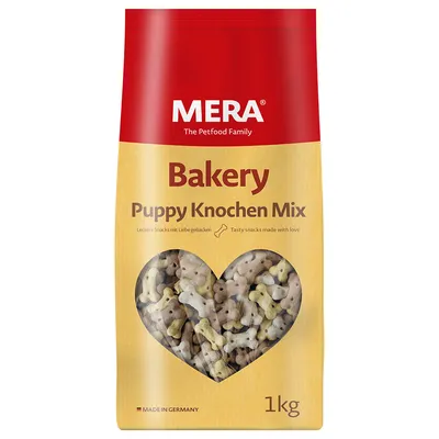 MERA Bakery Puppy Knochen Mix, pachet 1 kg, snacks în formă de os pentru căței, fereastră transparentă cu biscuiți colorați. Text vizibil: Made in Germany, Tasty snacks made with love.