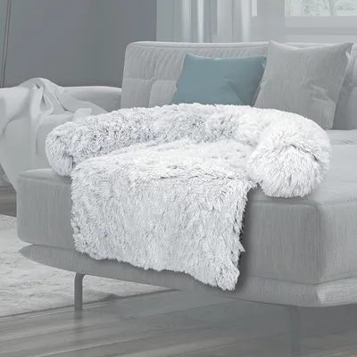 Weiches, weisses Plüschkissen in U-Form auf grauem Sofa, geeignet als gemütliche Liegefläche oder Dekoration.