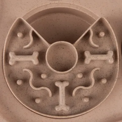 Round feeding toy made of plastic with bone and curve shapes for slow feeding.