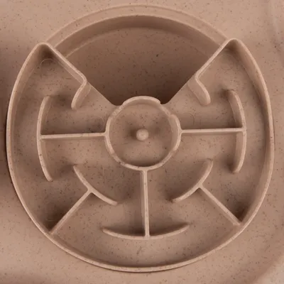 Round feeding maze made of beige plastic with several partitions for slow feeding.