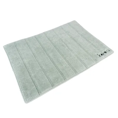Alfombrilla gris con diseño acolchado y pequeño logo en la esquina. Forma rectangular, apta para varios usos.