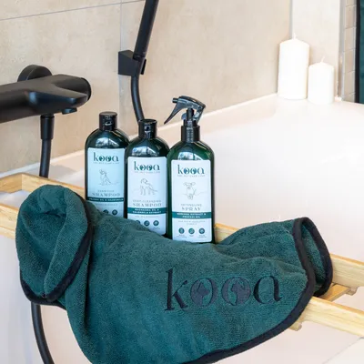 kooa Sensitive Shampoo, Deep-Cleansing Shampoo and Detangling Spray. Premium care brand for pets with bamboo tray and green towel.