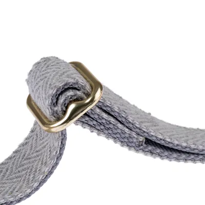 Közelkép egy szürke textil nyakörvről aranyszínű fém csattal.