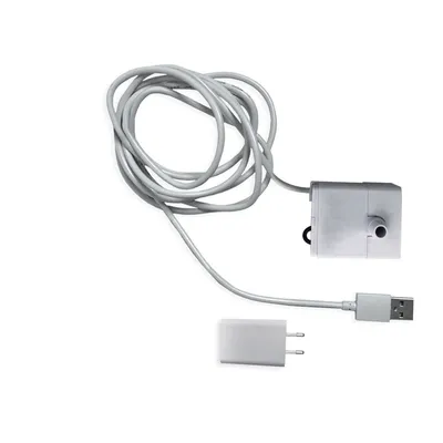 Cavo bianco con presa USB, adattatore di alimentazione e piccolo dispositivo in plastica grigia con foro visibile. Nessun marchio o testo identificativo presente.