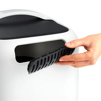 Hand showing the removal of a black filter from a white opening, presumably part of a pet accessory.