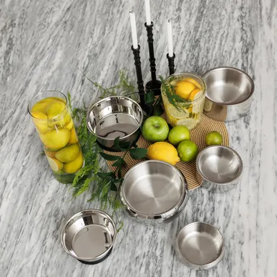 Rozsdamentes acél tálak szettje különböző méretekben, asztalon citrom, alma és gyertya dekorációval. Ideális háziállatok etetéséhez.