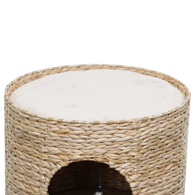 Round cat cave basket made of woven natural material with padded lying surface on top and entrance at the bottom.