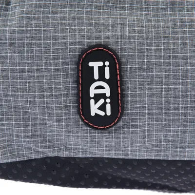 Tiaki-logotyp på grått tyg med svart och röd kant.