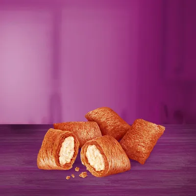 Image shows four filled, crunchy pillow-shaped treats with a creamy centre, displayed on a purple surface. Two treats are broken open to reveal the filling inside.