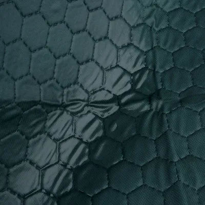 Nahaufnahme eines dunkelgrünen, wasserabweisenden Stoffes mit hexagonalem Muster.