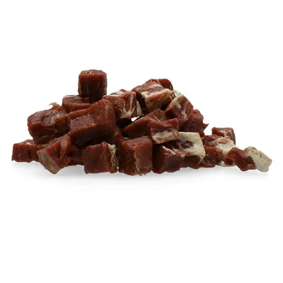 Hromádka malých hnědých kostek pamlsků s bílými proužky, bez viditelného obalu nebo značky.