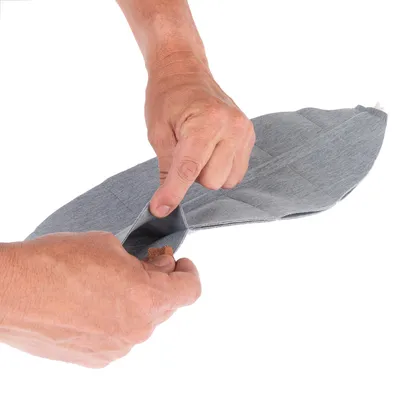 Main insérant une friandise dans une poche d’un accessoire en tissu gris, ouverture visible au centre de l’image.