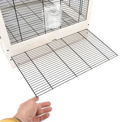 Cage en bois et métal avec porte grillagée ouverte, main tenant la grille, abreuvoir transparent fixé à l'intérieur.