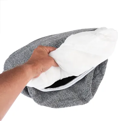 Mano che mostra un cuscino interno rimovibile in tessuto bianco in una fodera grigia con cerniera.