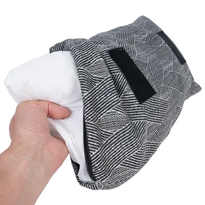 Hand zeigt herausnehmbares Innenkissen aus einem schwarz-weiss gemusterten Bezug mit Klettverschlüssen.