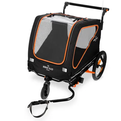 Nomad Tales cykelvagn i svart med orangefärgade detaljer, nätfönster och handtag. Med dragkrok och två stora hjul.