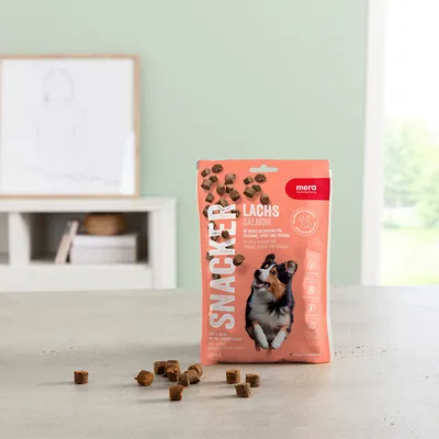 Mera Snacker laks, 200g. Ideel som belønning ved træning, sport og aktivitet. Made in Germany. Synlige hundesnacks spredt på bord.