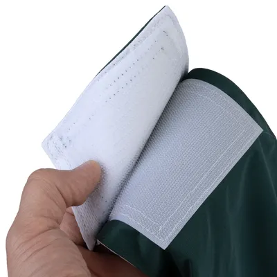 Nahaufnahme eines Klettverschlusses an einem grünen Stoff, geöffnet und von einer Hand gehalten.
