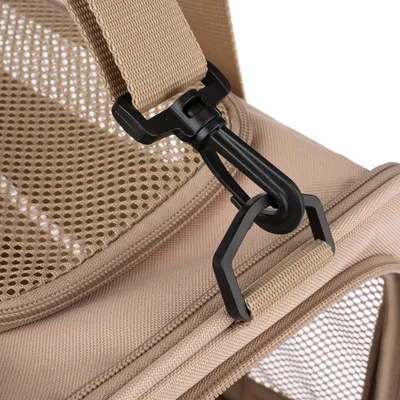 Détail d’une sangle beige avec mousqueton en plastique noir sur sac de transport en tissu et maille filet beige, fermeture éclair visible.