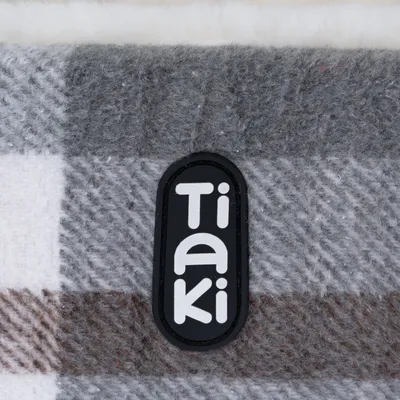 Tiaki logo on grey and brown checked fabric.