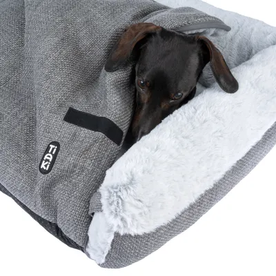 Tiaki Hundedecke in Grau mit weicher, weisser Plüsch-Innenseite. Dackel liegt teilweise unter der Decke.