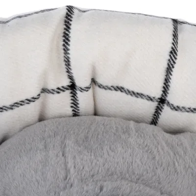 Close-up van een huisdierenbed met grijs, zacht oppervlak en witte stof met zwart ruitpatroon.