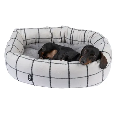 Hondenbed met wit ruitpatroon en grijs ligvlak. Hond ligt ontspannen in het bed. Merk Trixie zichtbaar aan de zijkant van het bed.