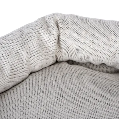 Primer plano de tela beige texturizada con diseño acolchado, posiblemente parte de una cama o cojín para mascotas.