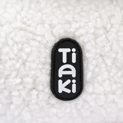 Tiaki logo on white textured fabric.