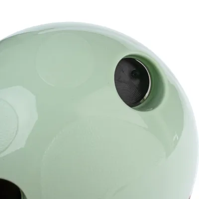 Detalj zelene plastične kugle s okruglim otvorom i reljefnim kružnim uzorcima na površini. Vidljiv je dio unutrašnjosti kroz otvor.