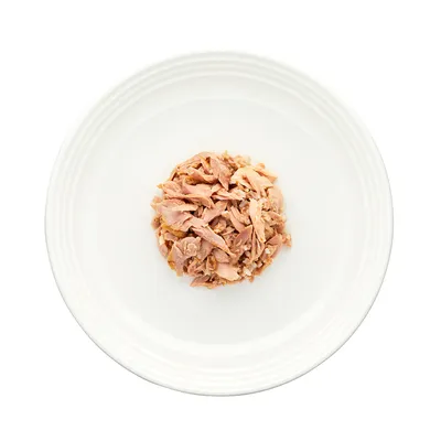 Portie natvoer met stukjes vlees op een wit bord, zonder zichtbare verpakking of merknaam.