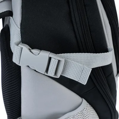 Gros plan sur une sangle réglable en tissu gris avec boucle plastique sur un sac noir et gris, fermeture éclair visible à droite.