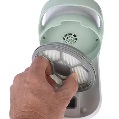 Hand showing how a filter is inserted into a green air purifier.