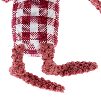 Jouet pour animal en tissu à carreaux rouges et blancs, pattes en peluche rose texturée visibles. Corps rectangulaire partiellement visible.
