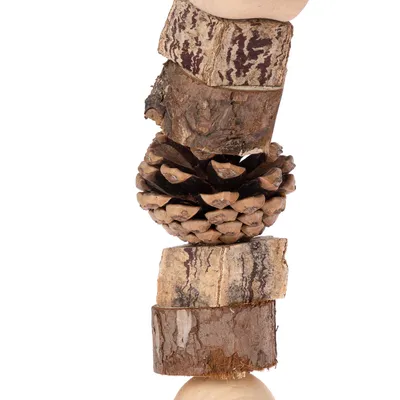 Jouet composé de rondins de bois, écorce et pomme de pin empilés verticalement, matériaux naturels visibles.