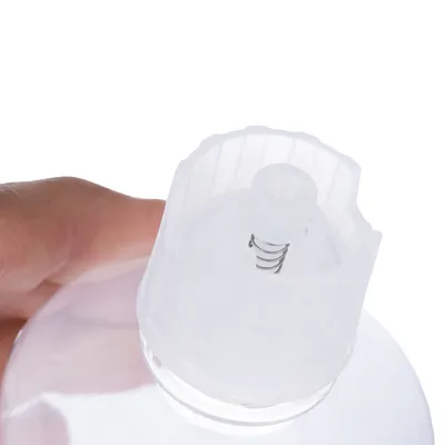 Nahaufnahme einer transparenten Flasche mit Federmechanismus im Deckel, gehalten von einer Hand.