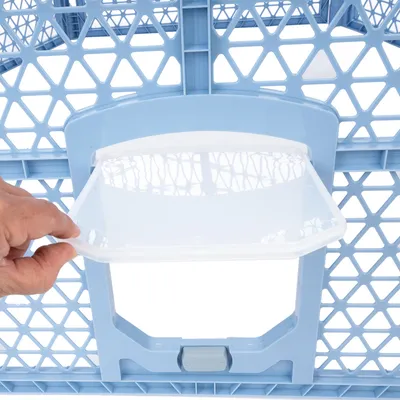 Mână deschide un capac transparent la o grilă albastră din plastic, probabil parte a unei cuști de transport pentru animale.