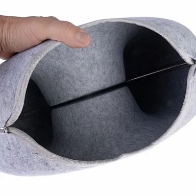 Saco cinzento de feltro com fecho de correr, aberto e segurado à mão, mostra interior com barra metálica para estabilização.