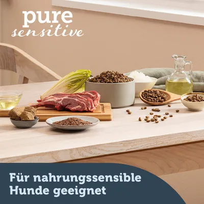 pure sensitive. Für nahrungssensible Hunde geeignet. Zutaten: Fleisch, Chicorée, Leinsamen, Öl und Trockenfutter auf einem Holztisch.