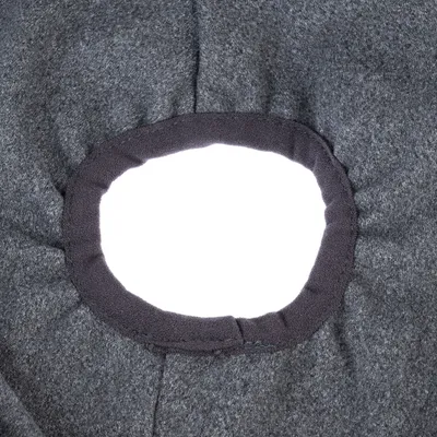 Vue rapprochée d'une ouverture ronde bordée de tissu noir sur une surface en tissu gris, sans marque ni texte visible.