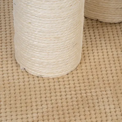 Detailný záber na sisalové lano okolo stĺpa škrabadla na béžovom koberci.