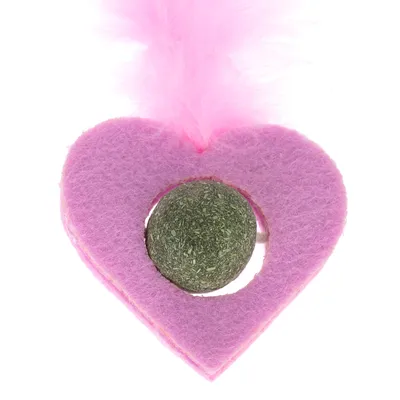 Jouet en forme de cœur rose en feutre avec une boule verte au centre et plume rose sur le dessus, matériaux visibles : feutre, herbe compressée, plume.