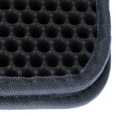 Detailný záber na čierny, včelí plást tvarovaný povrch so sivým, textúrovaným okrajom. Viditeľné materiály: plast a textília.