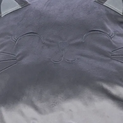 Graues Stoffdesign mit gesticktem Katzengesicht, inklusive Ohren und Schnurrhaaren.