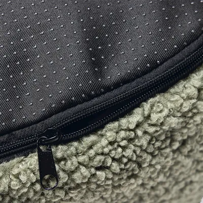 Gros plan sur une housse de coussin pour animal avec fermeture éclair, dessus en tissu à picots antidérapants et dessous en tissu bouclé vert clair.