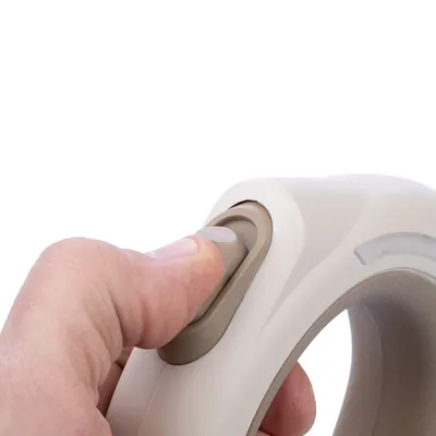 Primo piano di una mano che aziona un interruttore scorrevole beige-grigio su un'impugnatura ergonomica.