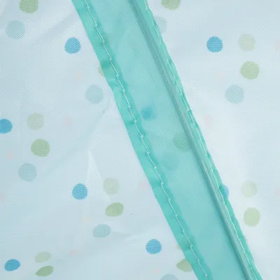 Close-up of a turquoise zip on white fabric with colourful dots.