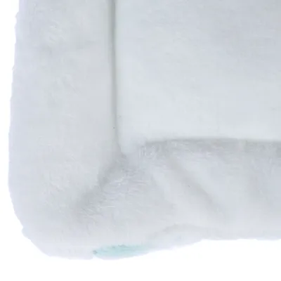 Gros plan sur un coin de coussin ou tapis blanc en tissu peluche, sans marque ni texte visible.