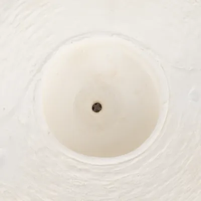 Približeni prikaz bijele plastične podloge s crnom točkom u sredini, moguće dio proizvoda ili dodatka.