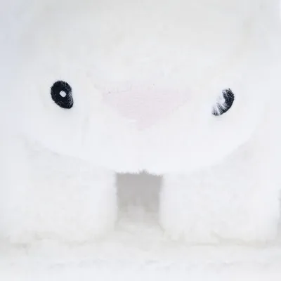 Nahaufnahme eines weissen Plüschtiers mit schwarzen Augen und rosa Nase. Produktdetails nicht sichtbar.